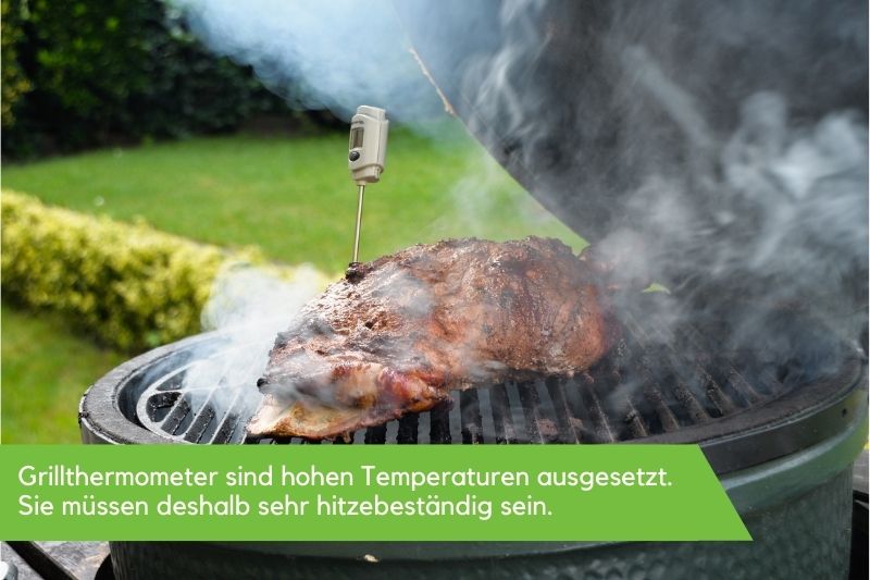 Grillthermometer in einem Stück Fleisch, welches auf einem rauchenden Grill liegt